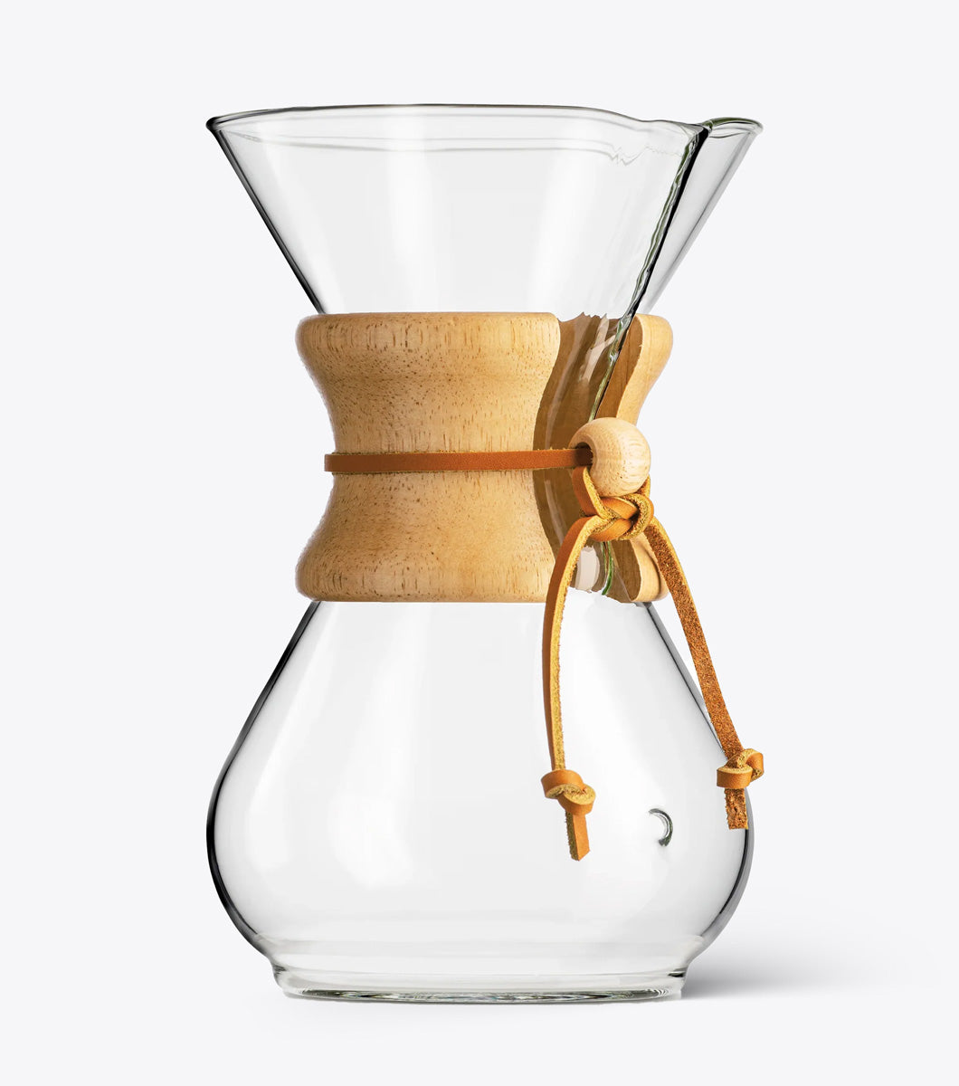 Clear glass coffee maker with wooden collar and leather tie on a white background
