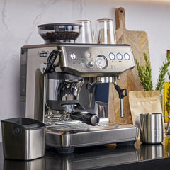 Sage silver espresso machine on a kitchen counter with various items in the background