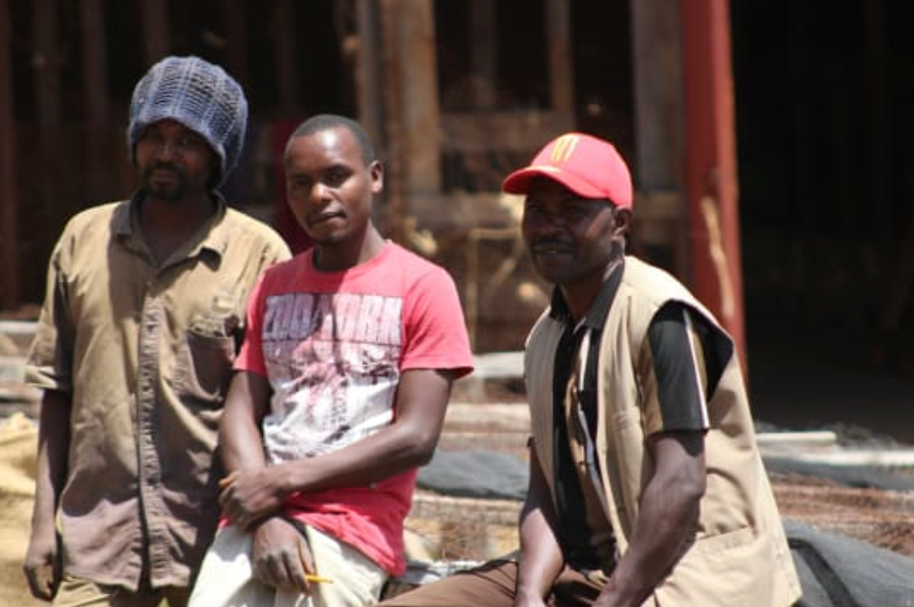Three men sitting together outdoors in a coffee farm